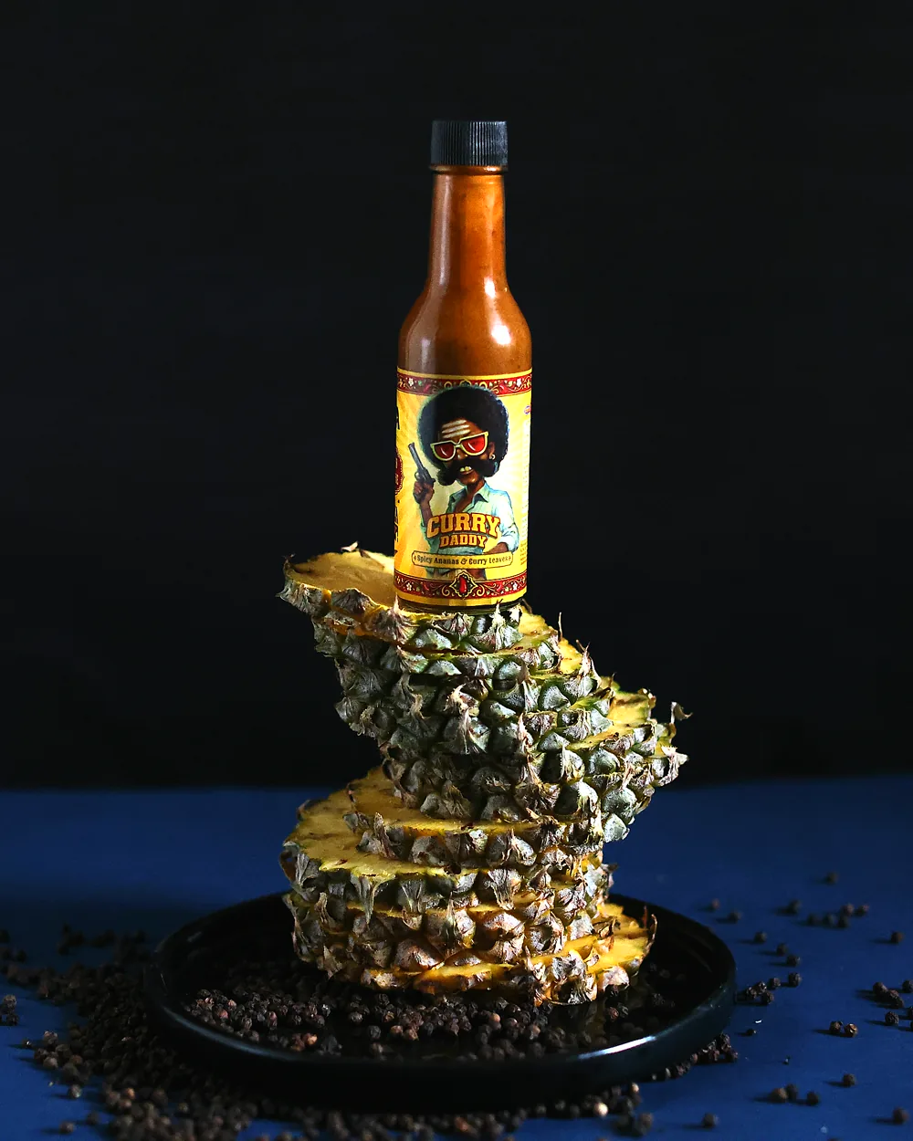 A bottle of Curry Daddy standing on a stack of pineapple slices