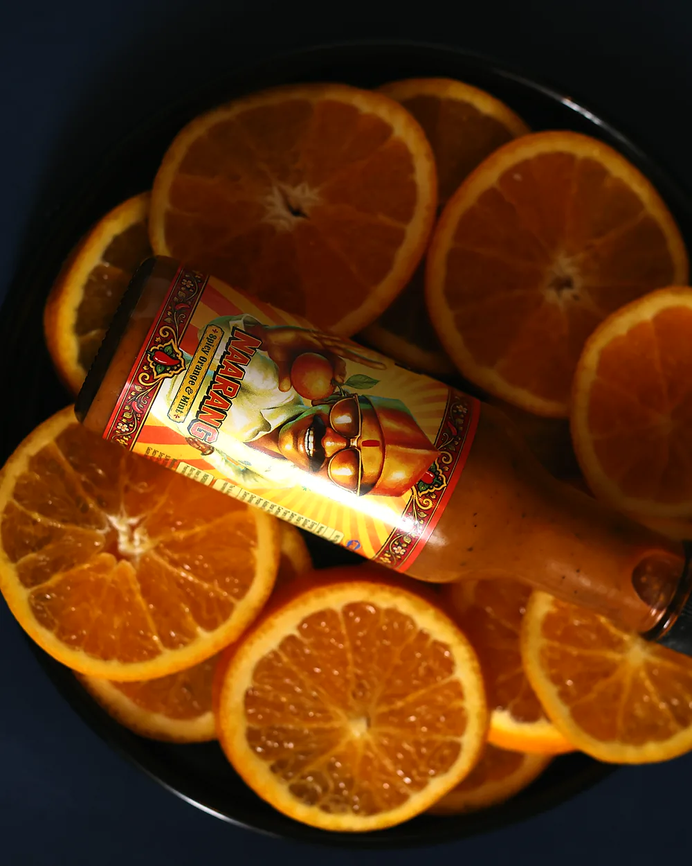A bottle of Naarang lying on a plate of orange slices